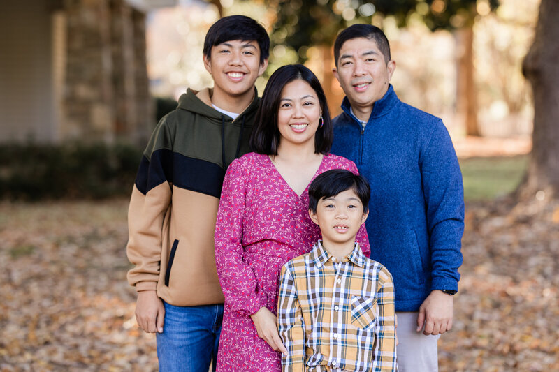 Group of females posed and smiling on a football field in graduation gowns.
