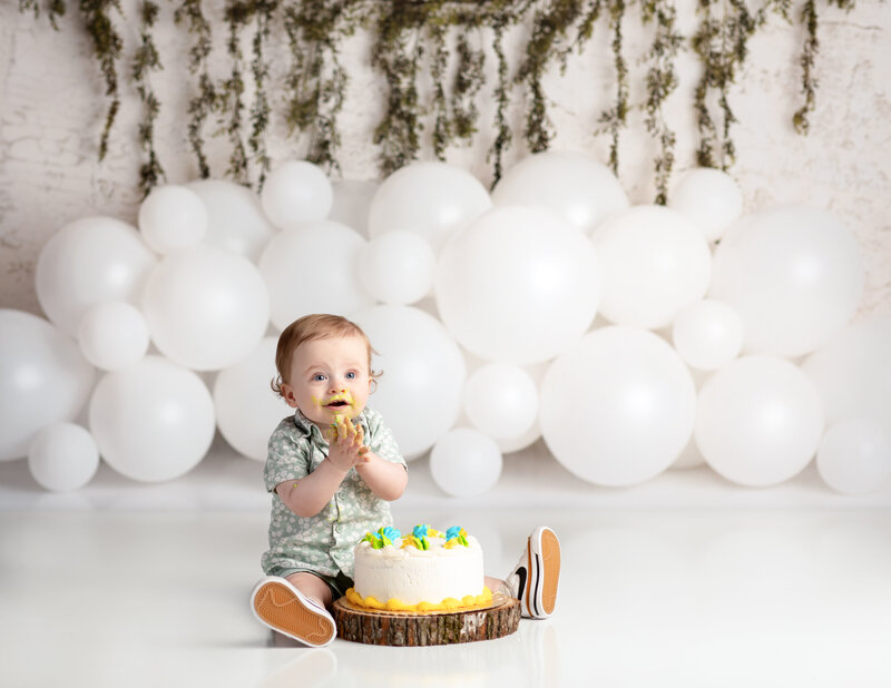 one year old boy sitting with cake for first birthday cake smash session