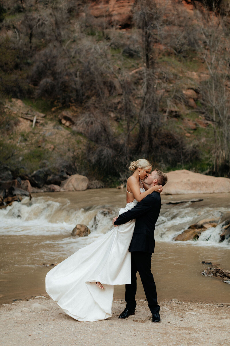 Bride and groom standing on a cliff edge in Zion at sunrise.