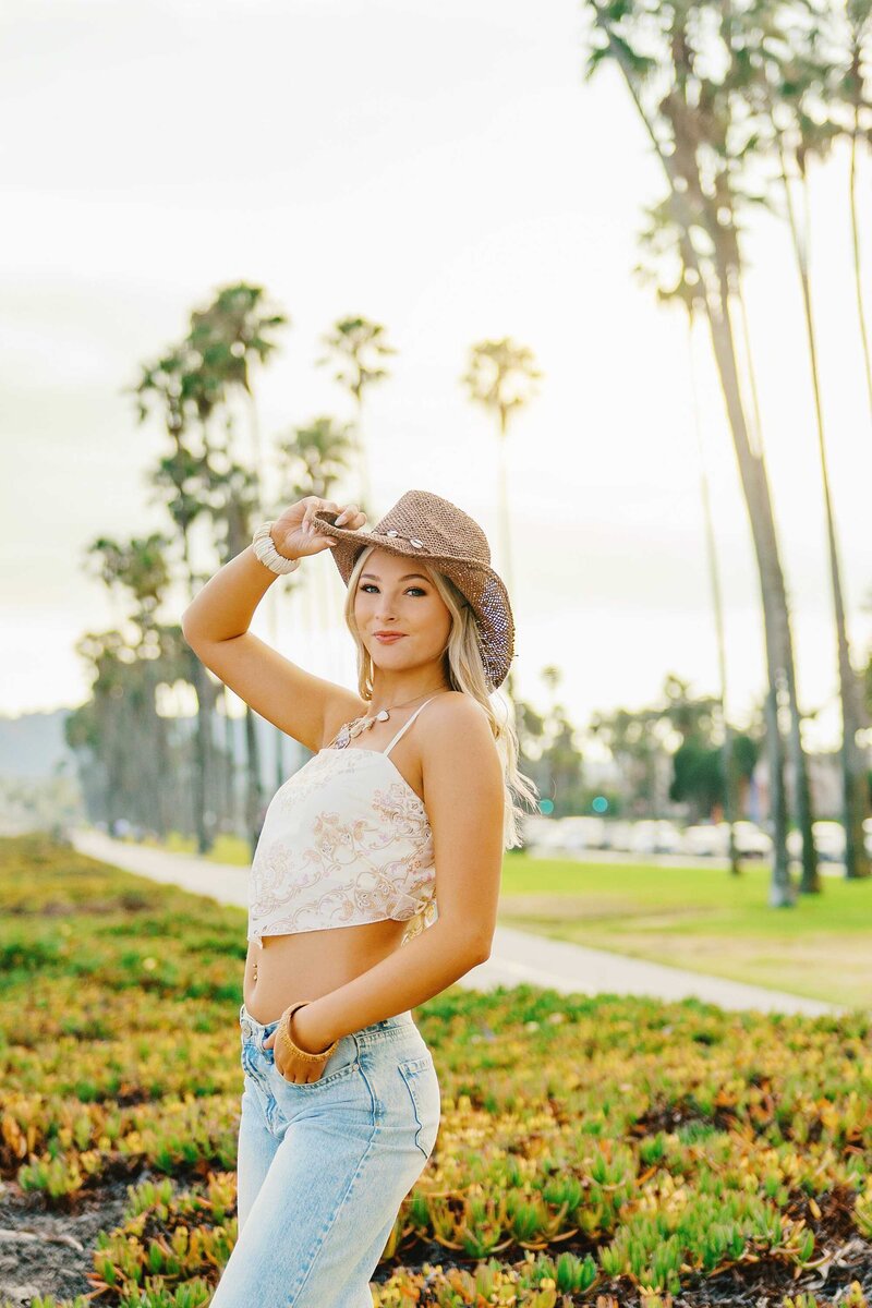 Girl wearing sunglasses beneath palm trees.