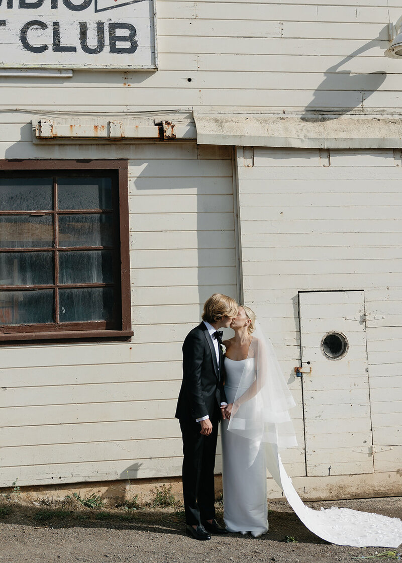 Bride and groom pose on a city balcony