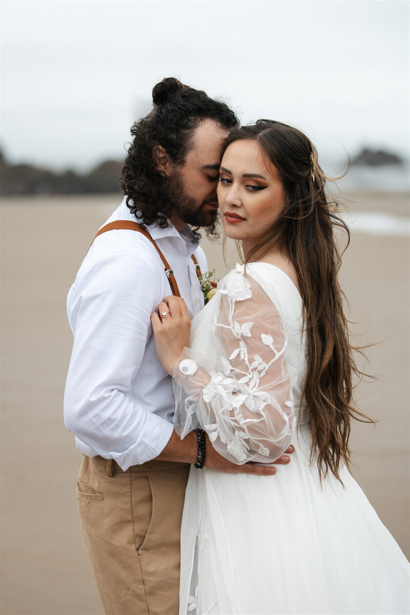 A bride and groom embrace on the beach during their elopement on Cannon Beach in Oregon
