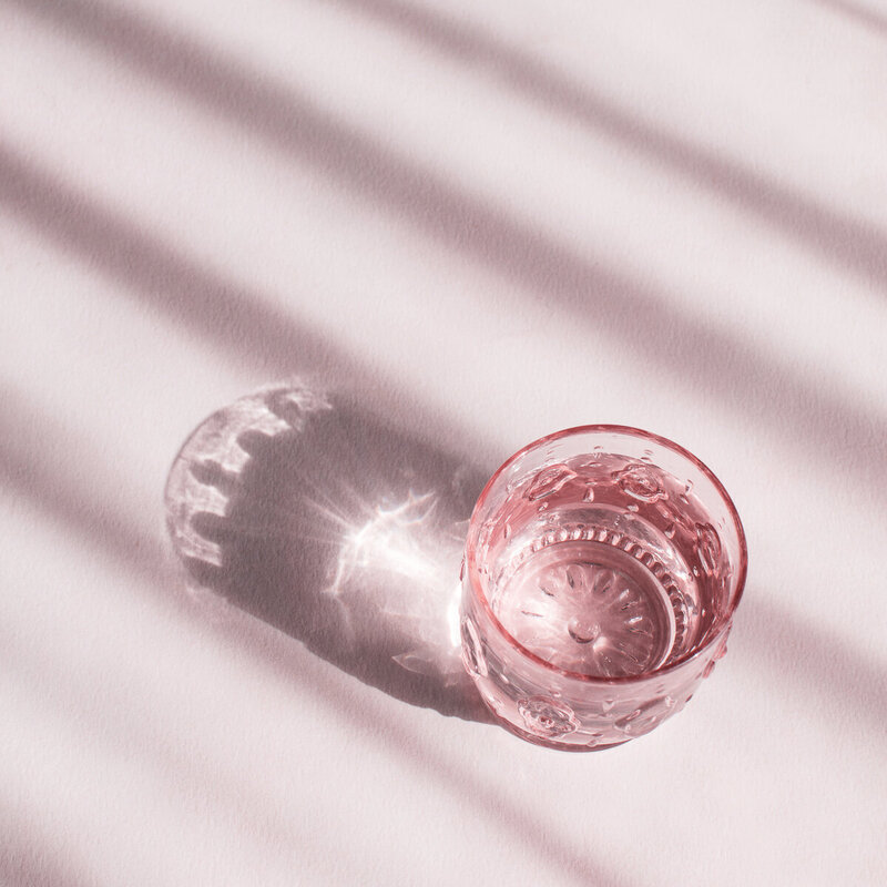 Pink cup reflecting sunlight on pink background