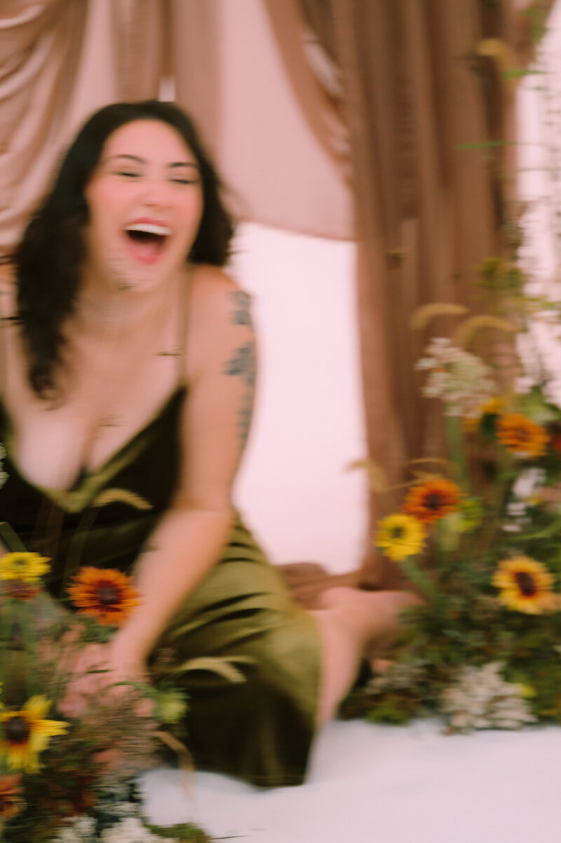 Colleen laughs while sitting surrounded by flowers.