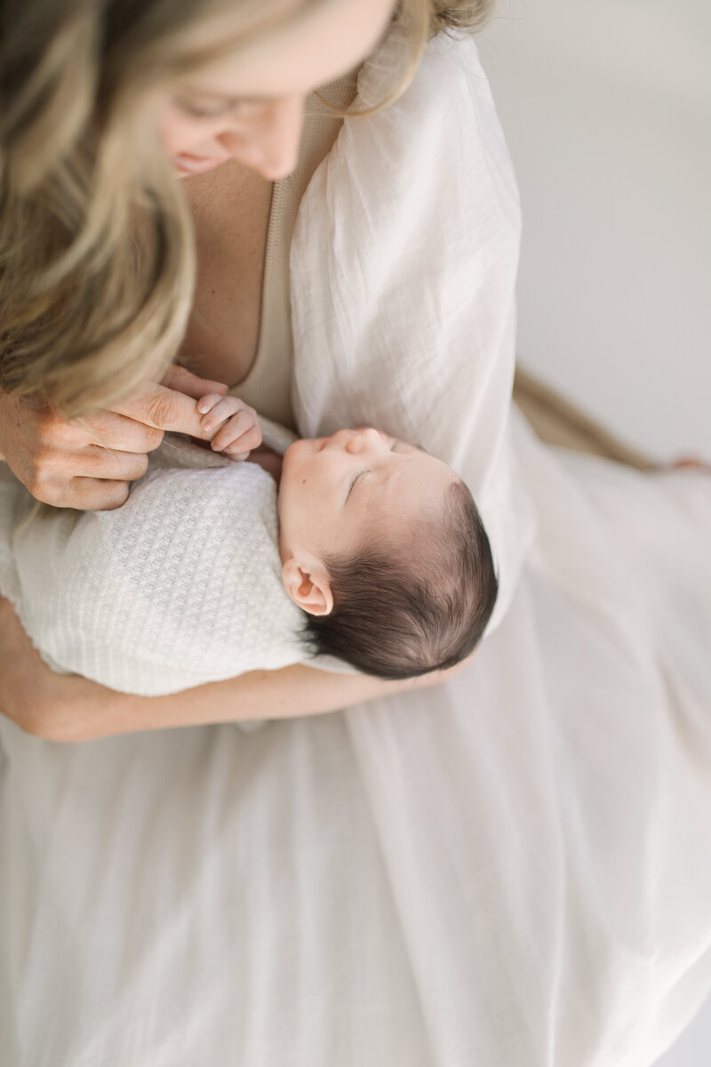 Mother and newborn baby holding hands