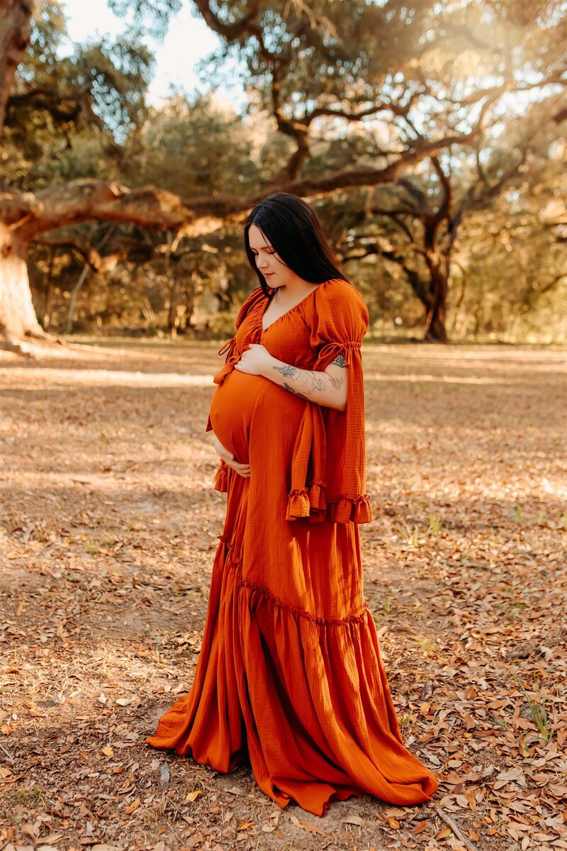Cleveland TX maternity session - mother-to-be holding baby bump  in a flowy rust gown