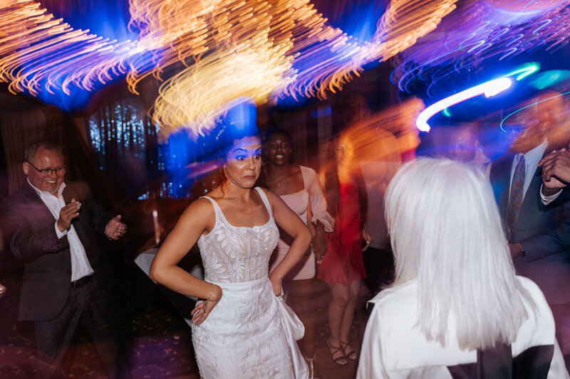 Bride turning up solo on the dance floor with light trails from a shutter drag effect capturing the energy
