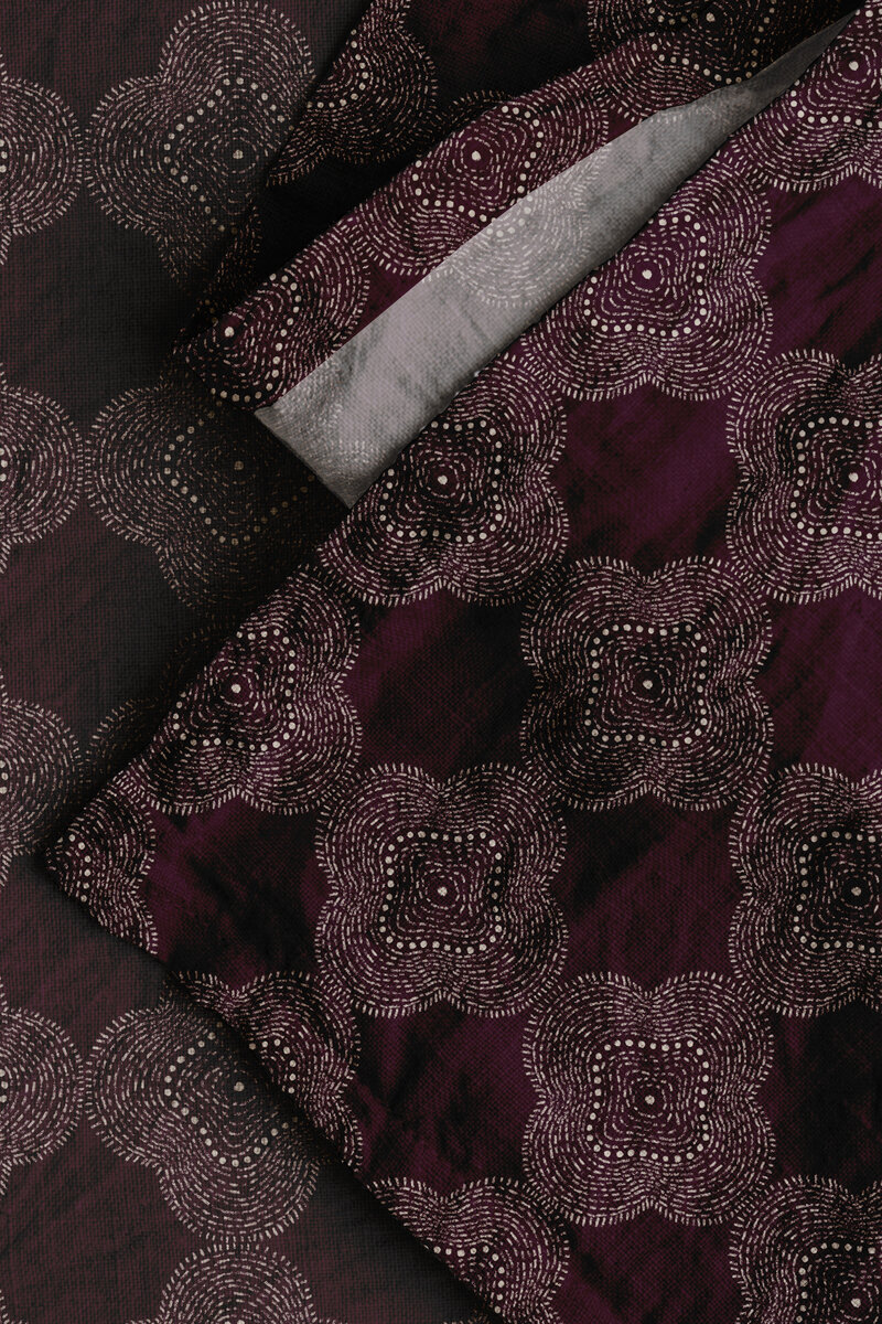 Rich jewel toned mulberry color fabric printed with a highly textured hand drawn pattern in a moroccan stitched style designed by Atlas Greene