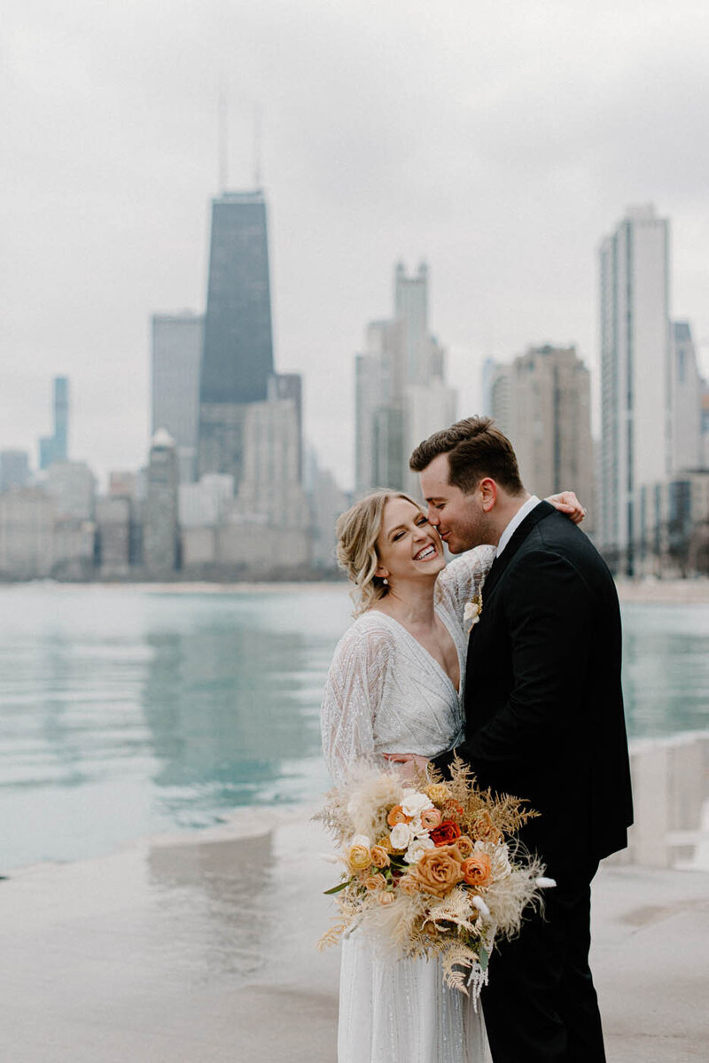 bride and groom cozy up in front of the chicago skyline