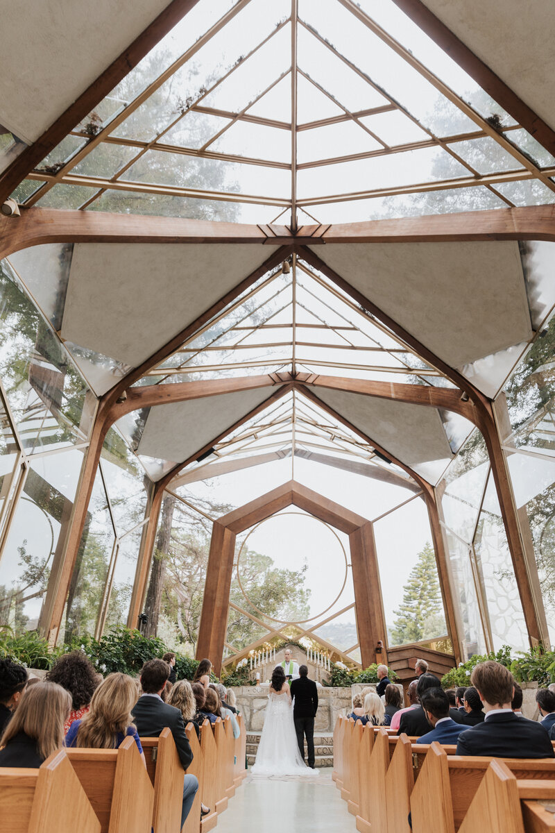Alex and Travis exchange vows in a modern glass chapel ceremony, planned by Beyond the Event and photographed by Coyprint.
