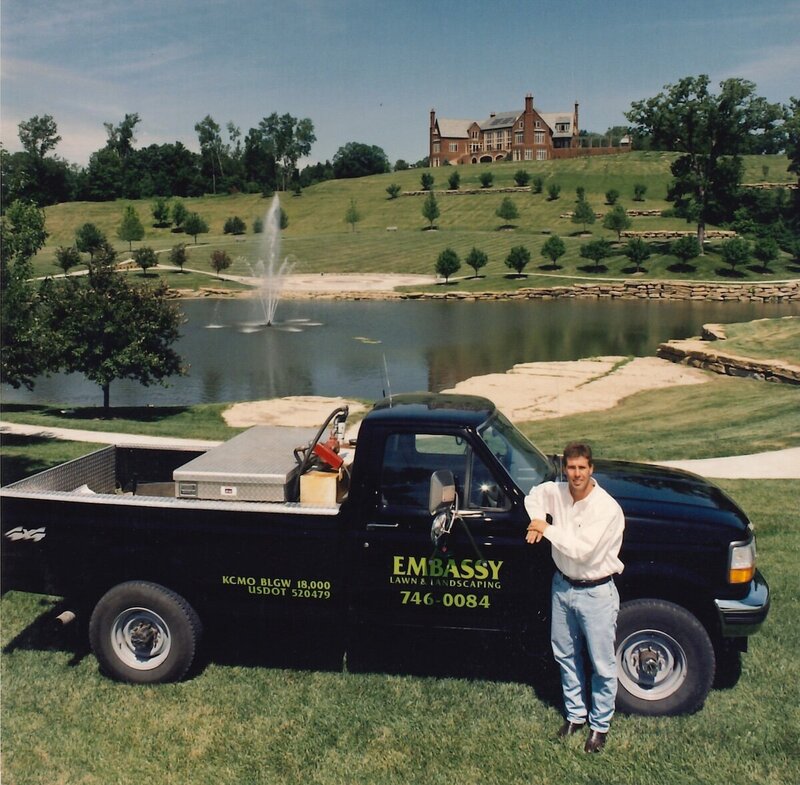 archive image of the founder of Embassy Landscape standing in front of a black work truck from the 80s