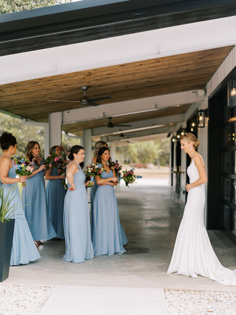 Bride doing a first look with her bridesmaids in blue dresses
