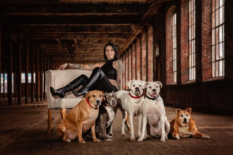 Woman with tattoos poses in the industrial McKinney Cotton Mill with her five dogs.