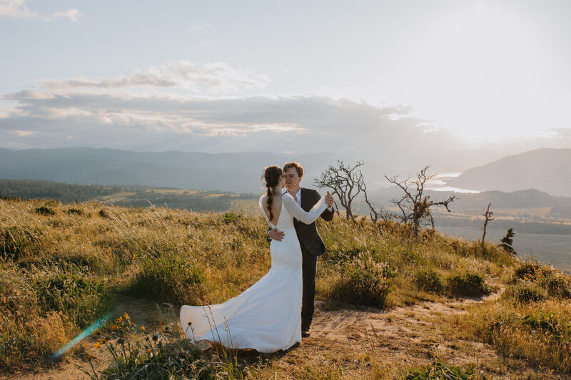 Bride and groom dancing on a grassy mountain top