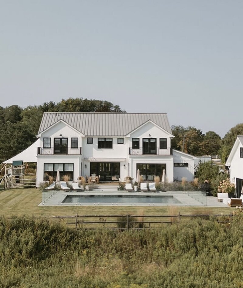 Black wood modern farmhouse venue rental featuring muskoka chairs and a pool