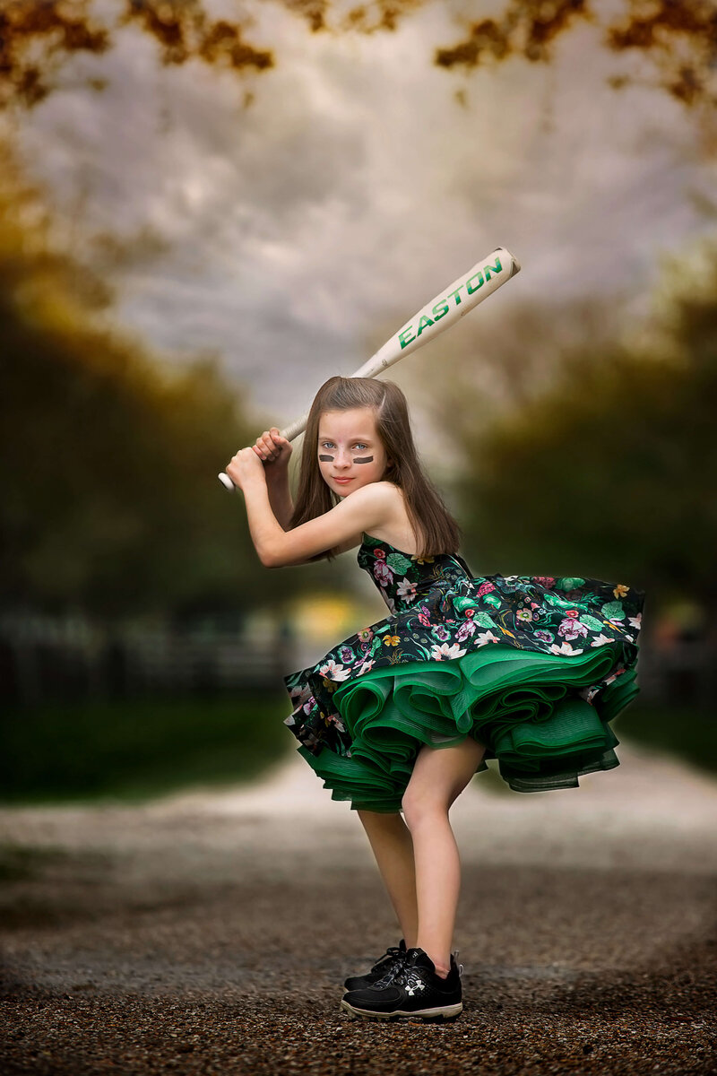 Little girl dressed up and holding a softball bat