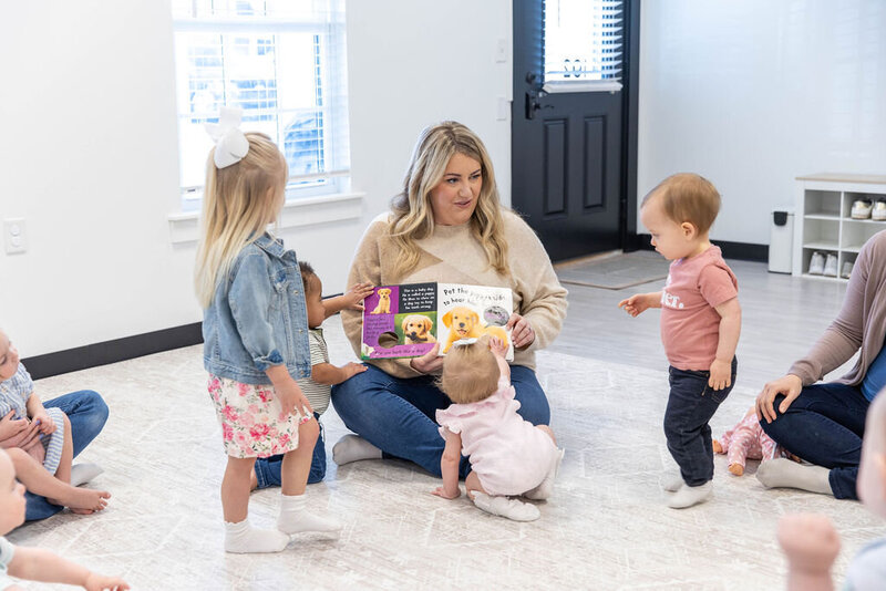 Woman reading a book to three toddlers