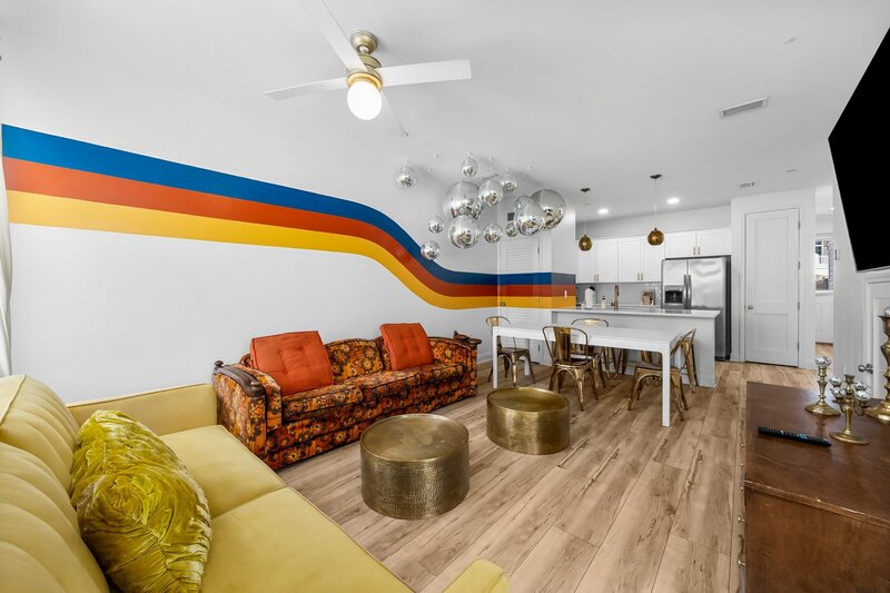 Wide shot of Groovy Shack’s main floor showing a retro living room and full kitchen with unique disco ceiling and dining space for ten.
