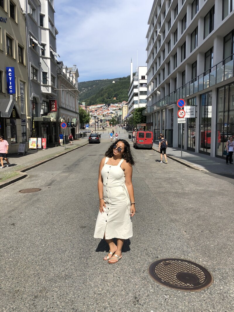 Women in a cream dress with blue sunglasses posing for a picture in the middle of the road