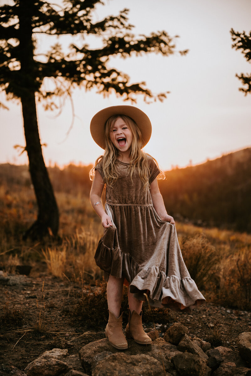 A beautiful little girl laughing while twirling her dress by Joyfolie in the Mountains near Fort Collins