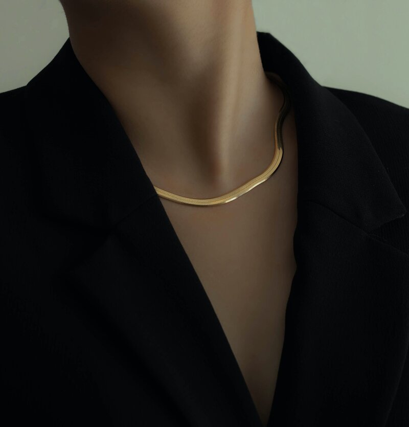 Detail of a gold necklace on the neckline of a black blazer
