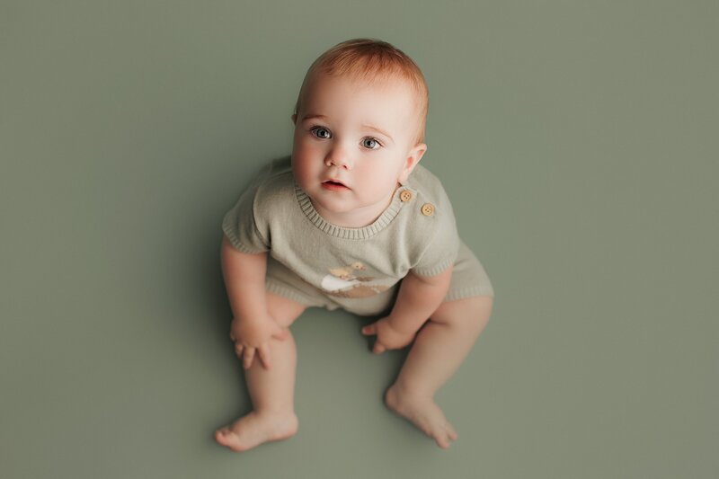 Baby laughing while holding toy during interactive milestone session
