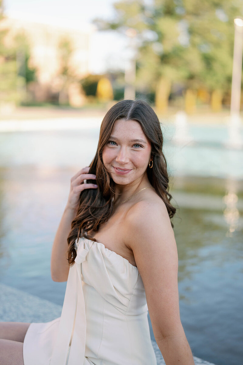 Graduate of Western Michigan University smiling in front of Miller Fountain during her senior photo session.