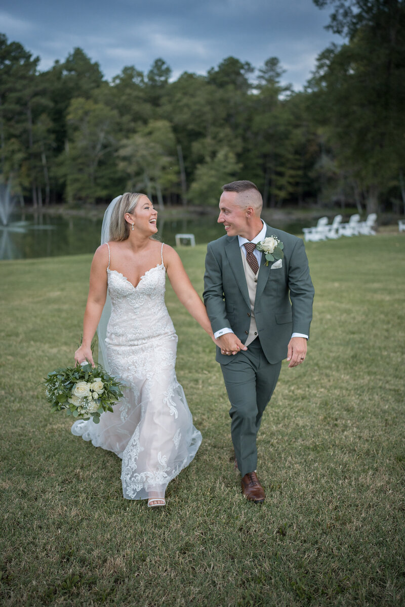 Bride and groom walking and smiling with a fountain in the background.