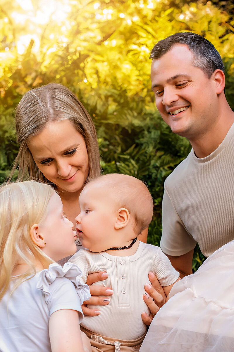 Captured in the heart of Brisbane's lush parklands, this family photo by Paula Jane Photography radiates joy and togetherness. Surrounded by the vibrant greenery of Roma St Parklands, the family shares laughter and embraces.