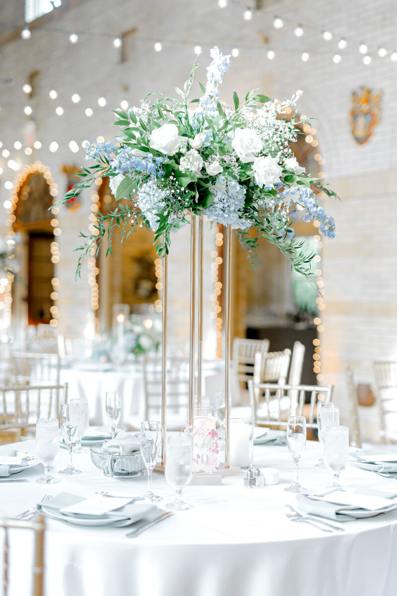 Tall wedding centerpiece with white and blue flowers on reception table