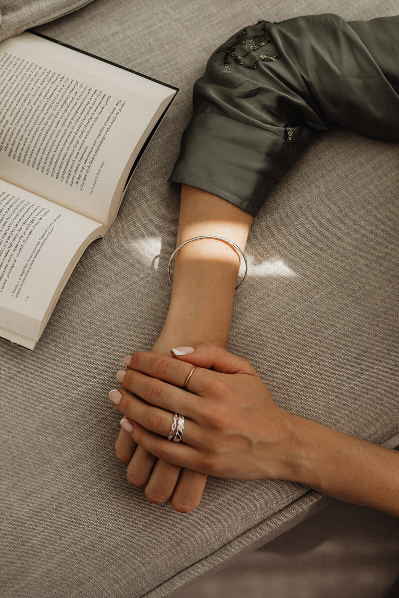 Woman’s hands resting on a couch as she reads a book, confident that an expert is supporting the financial health of her business. Say goodbye to financial stress and focus on scaling—Ataraxis Financial provides expert bookkeeping, accurate financial records, and strategic insights to help you reach your 7-figure goals with confidence.