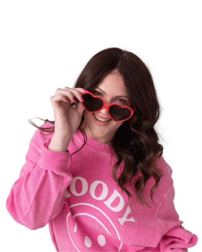 Emily wearing a pink sweater and heart shaped sunglasses.