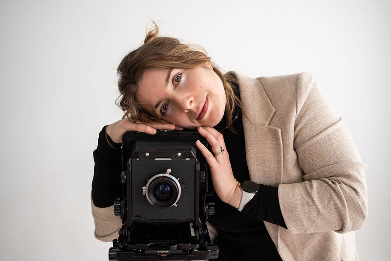 A person with their head resting on the top of an old school camera.