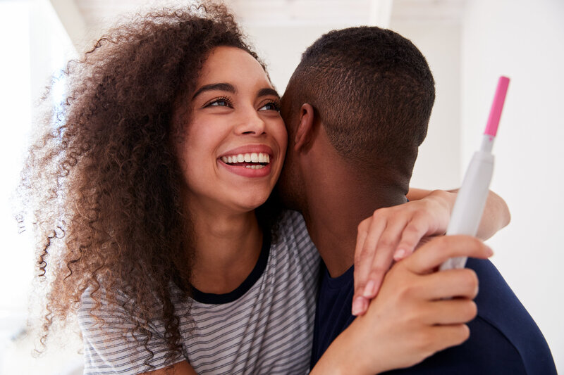 Black couple hugging in excitement of a positive pregnancy test