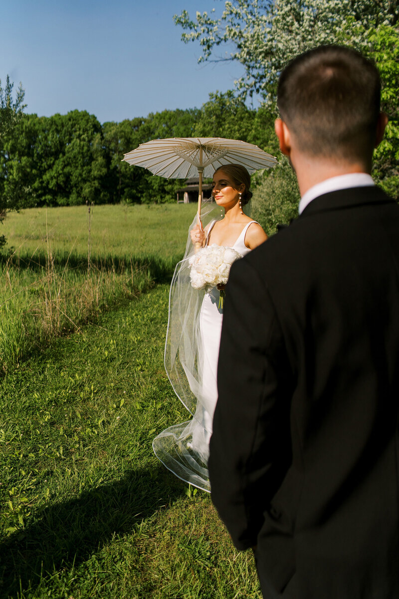 Wedding couple embracing in sunlit garden setting with peach and white bouquet.
