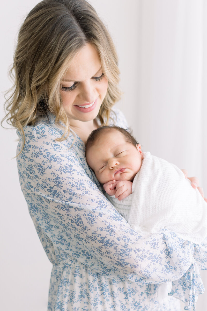 Mom in blue dress holding baby boy at newborn session