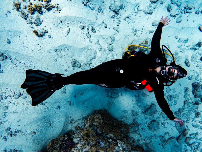 Shannon Lee, a Florida elopement photographer, shows herself in an underwater moment of a diver swimming gracefully above a vibrant coral reef.