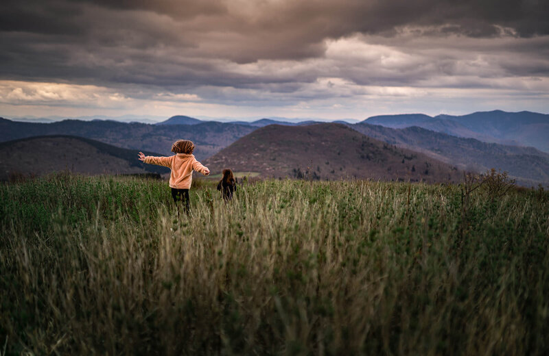 two little girls running through the grass on Black Balsalm knob near Asheville NC