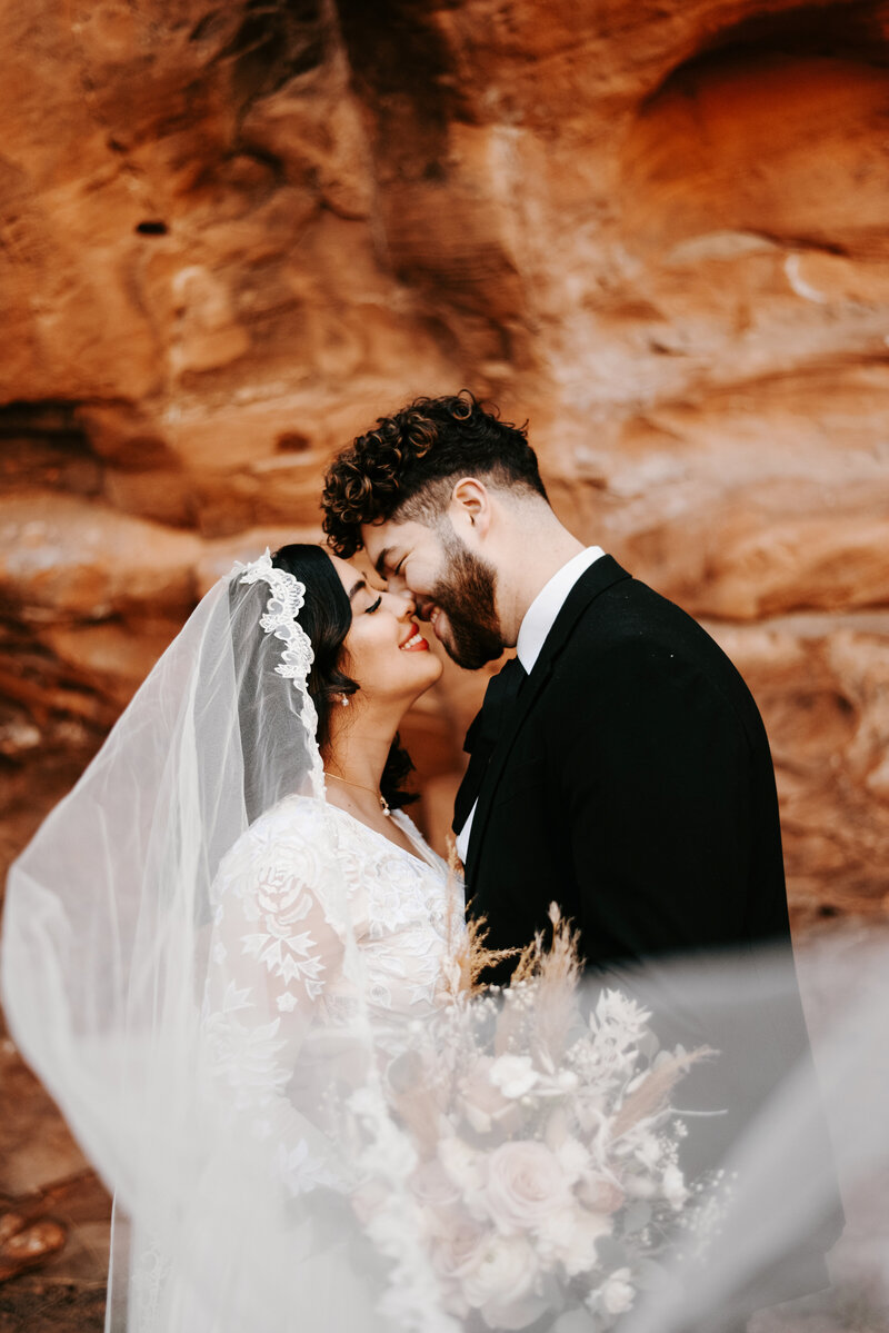 Bride and Groom eloping in Arches National Park in a wedding dress and black suit with a wedding arch.