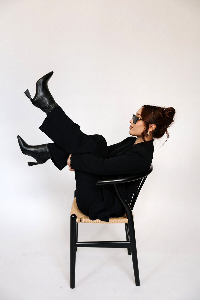 Professional female virtual executive assistant in a black blazer holding an open laptop, with a friendly smile