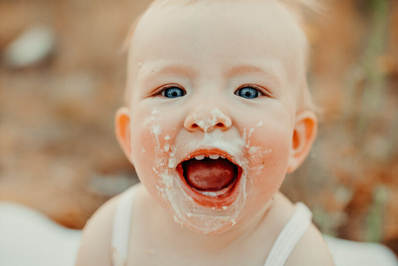 Baby girl smiling with cake on her face