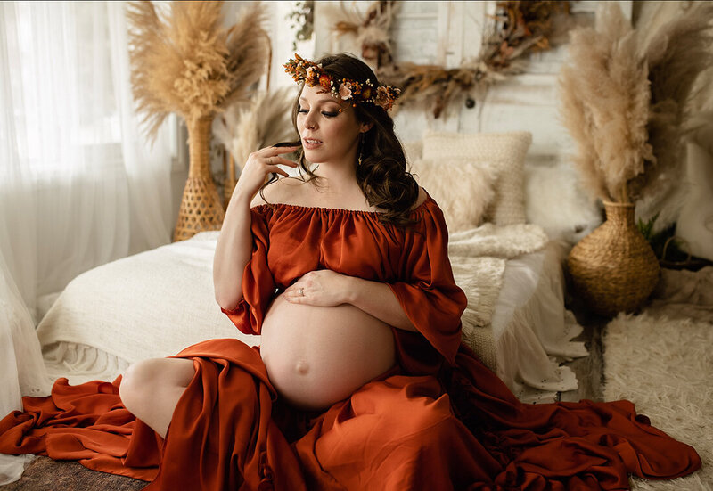 Pregnant mother in  rust two piece maternity dress with floral crown in boho studio