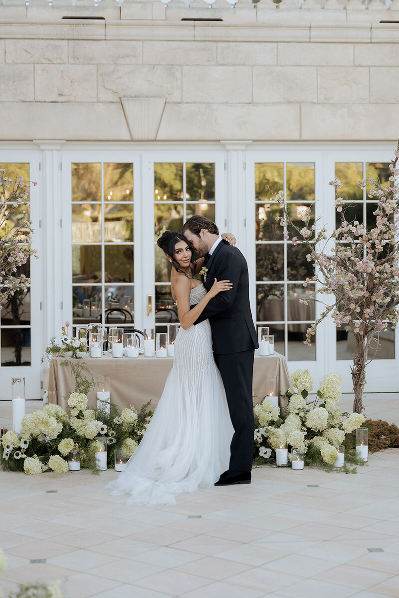 bride and groom pose in front of reception table with candles and hydrangeas