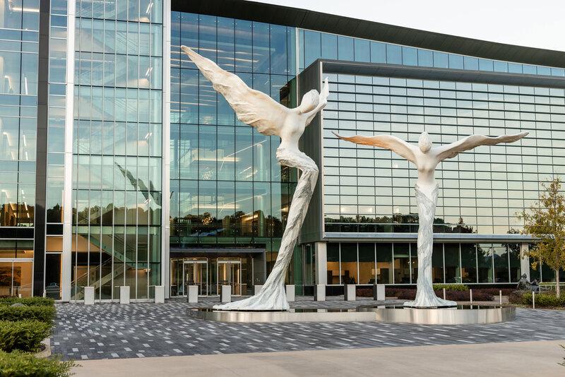 Modern commercial building with dramatic glass architecture and large winged sculptures, part of a landscape installation project by Better Lawns and Gardens in Little Rock, Arkansas.