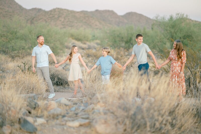 mom and dad and family walking in the desert in a line 