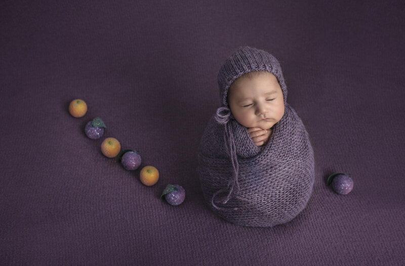 Newborn baby beautifully wrapped in soft, neutral fabric, peacefully sleeping in a classic and cozy pose during a fine art newborn photography session in Ottawa."