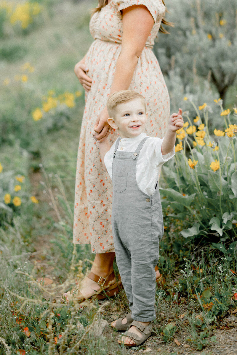 toddler and mom walking together in the park around flowers