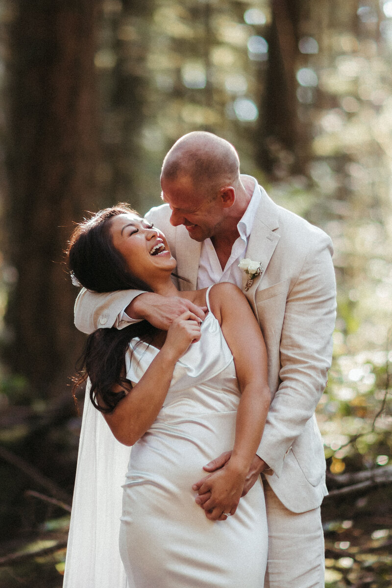 groom with his arms around the bride laughing together