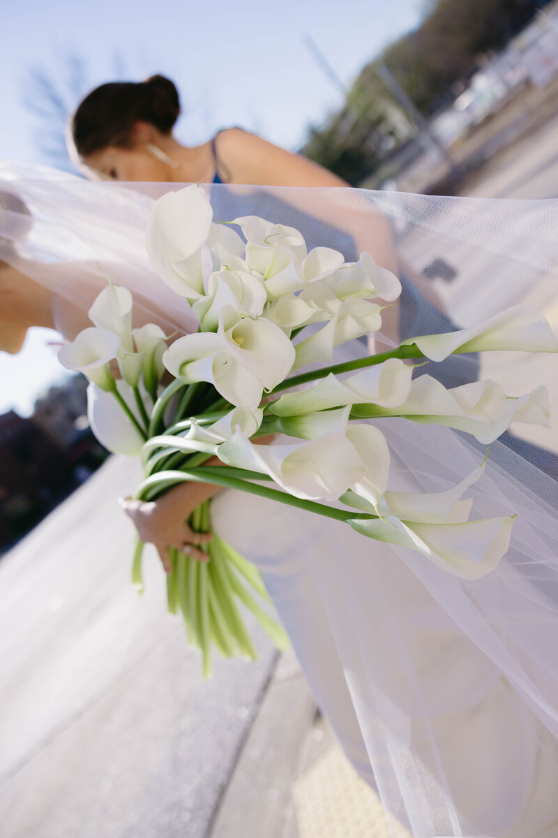 Bride holding white calla lily bouquet with flowing veil during outdoor Arkansas wedding, Clar Barron Photo.