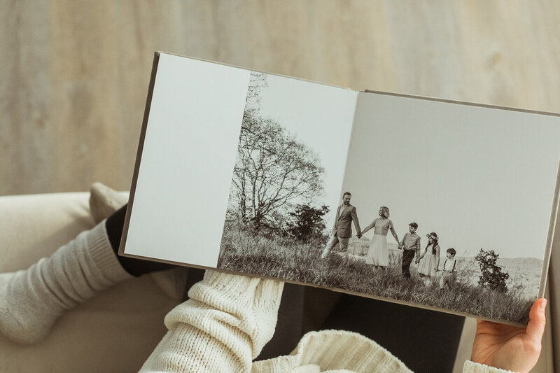 woman is snuggled on the couch with cozy socks flipping through a family photo album
